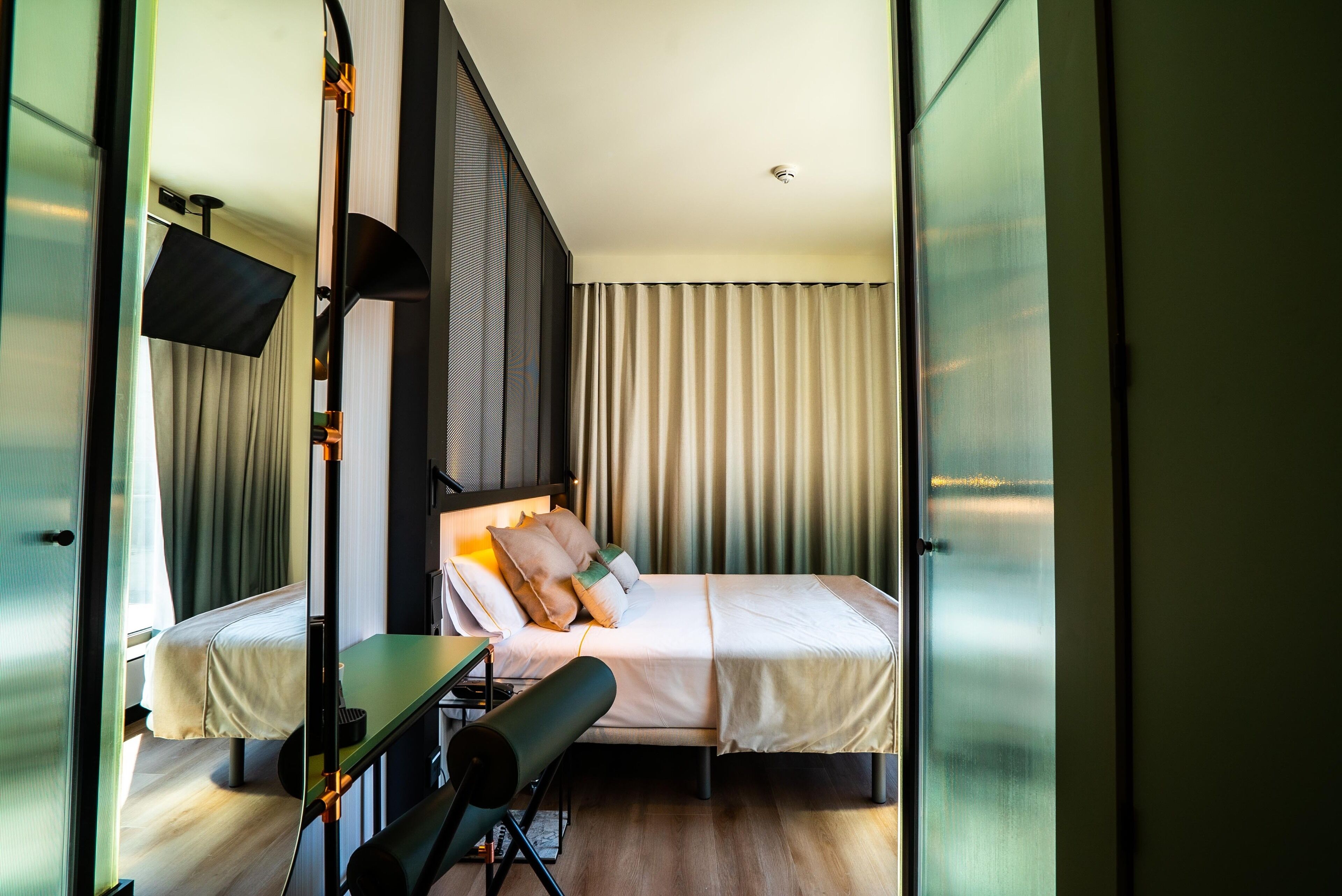 Ein modernes Hotelzimmer mit einem Bett, einem Schreibtisch und einem großen Fenster mit Vorhängen.