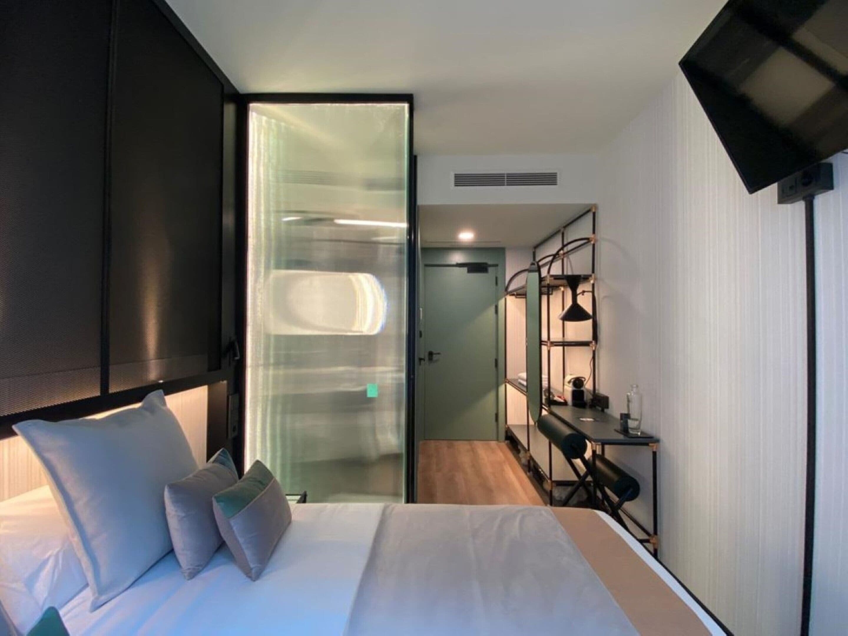Quarto de hotel moderno com cama, escrivaninha e closet espaçoso.