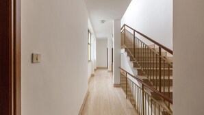 A hallway with a wooden staircase and a light switch on the wall.