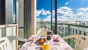 A balcony with a table set for breakfast, including muffins, coffee, and tea.