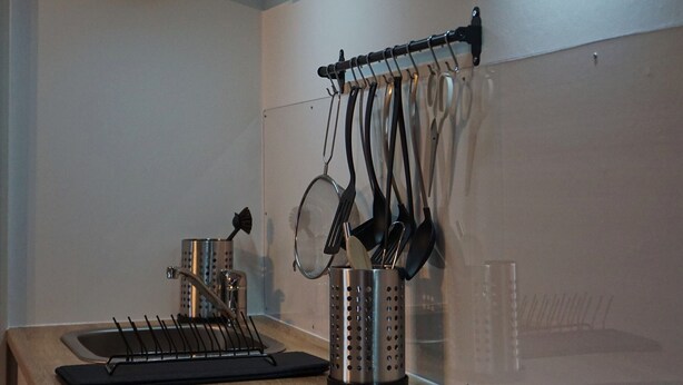 A modern kitchen with a stainless steel stove, a hanging pot rack, and a built-in oven. - 2 cozy apartments, near Heide Park - approx. 10 min walk, FeWo Friedrichseck (Soltau)