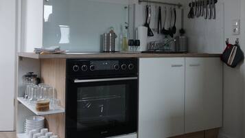 Une cuisine moderne dotée d’un four encastré, de meubles blancs et d’un plan de travail en bois.