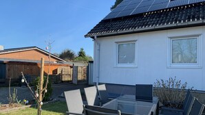 A residential property with a solar panel roof, a fenced backyard, and a patio area with outdoor furniture. - 2 cozy apartments, near Heide Park - approx. 10 min walk, FeWo Friedrichseck (Soltau)