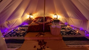 A tent with a bed, two lamps, a basket with towels, and a rug. - Glamping Octli - Santuario de las Luciernagas X NANTLI LIVING (Nanacamilpa)