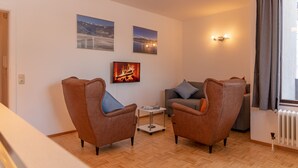 A living room with two brown armchairs, a grey sofa, a small white table, and a fireplace. - Apartment Six T Nine, balcony, near ski lift (Zell am See)