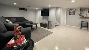 A modern living room with a black sofa, a coffee table, and a TV mounted on the wall. - Newly renovated 3BR/2BA home - 10 mins from EWR (Elizabeth)