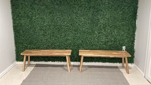 Two wooden benches against a green artificial wall, with a grey rug on the floor. - Newly renovated 3BR/2BA home - 10 mins from EWR (Elizabeth)
