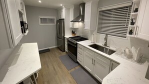 A modern kitchen with white cabinetry, stainless steel appliances, and a grey countertop. - Newly renovated 3BR/2BA home - 10 mins from EWR (Elizabeth)