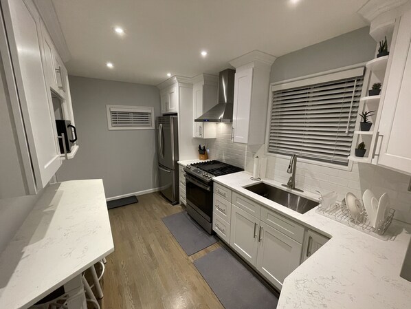 A modern kitchen with white cabinetry, stainless steel appliances, and a grey countertop.