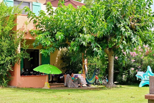 Uma casa com varanda, rede e guarda-sol verde.