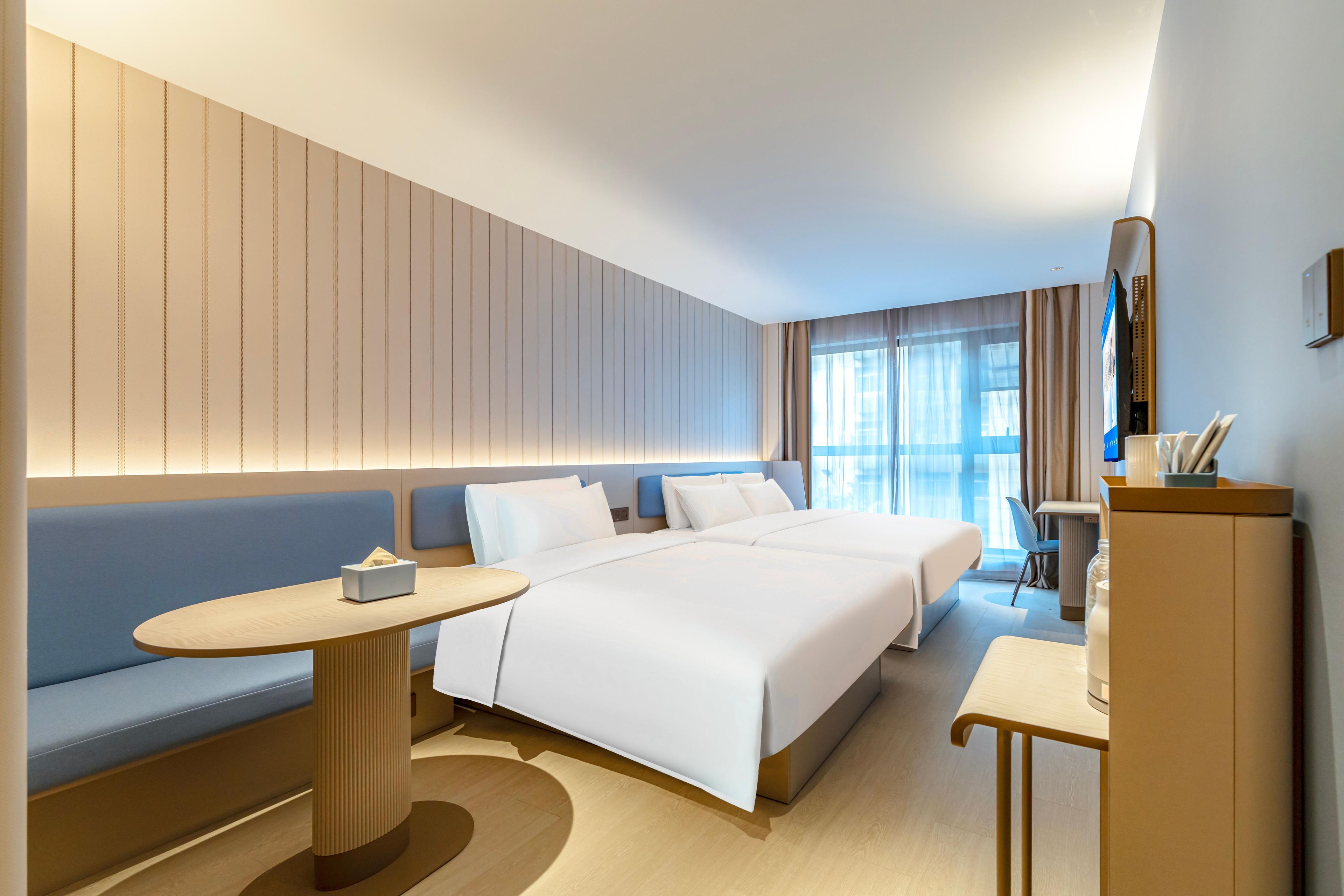 Een moderne hotelkamer met een groot bed, een zithoek, een bureau en uitzicht op de stad.