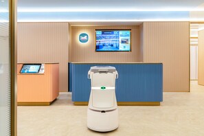 A reception area with a digital kiosk, a reception desk, and a robotic vacuum cleaner. - Hanting Hotel (Xi'an)