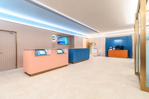 A hotel reception area with a reception desk, a television screen, and a coffee machine. - Hanting Hotel (Xi'an)