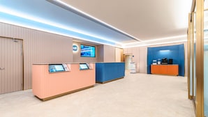 A hotel reception area with a reception desk, a television screen, and a coffee machine. - Hanting Hotel (Xi'an)