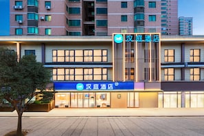 A hotel facade with multiple floors, large windows, and a prominent entrance with a blue sign. - Hanting Hotel (Xi'an)