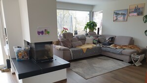 Una sala de estar con sofá, una mesa de centro, televisor y ventana con persianas.