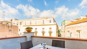 Eine Dachterrasse mit Tisch für zwei, einer Kaffeekanne und einem Croissant.