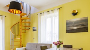 Ein Essbereich mit einem Holztisch, Stühlen, einer Wendeltreppe und einer gelben Wand mit einem Gemälde.
