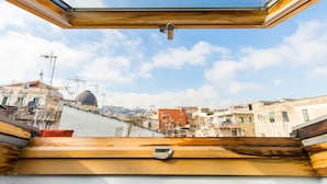 Blick aus einem Fenster mit Holzrahmen auf eine Stadtlandschaft mit Gebäuden und einer Kuppel.