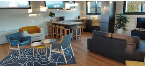 Uma sala de estar moderna com um sofá cinzento, poltronas azuis, uma mesinha de centro e um tapete estampado.