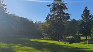 A grassy park with a picnic table and benches, surrounded by trees and a fence. - Cornerstone Ranch experience minutes to the beach and Rogue River (Gold Beach)