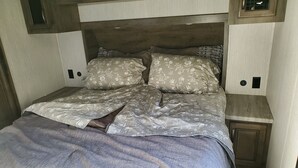 A bed with floral bedding, a wooden headboard, and two bedside tables with lamps. - Cornerstone Ranch experience minutes to the beach and Rogue River (Gold Beach)