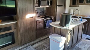A compact kitchen with wooden cabinets, a microwave, a stove, and a sink. - Cornerstone Ranch experience minutes to the beach and Rogue River (Gold Beach)