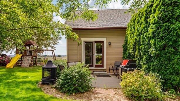 Une maison avec un patio, un ensemble de jeux pour enfants et une vue sur l’eau.