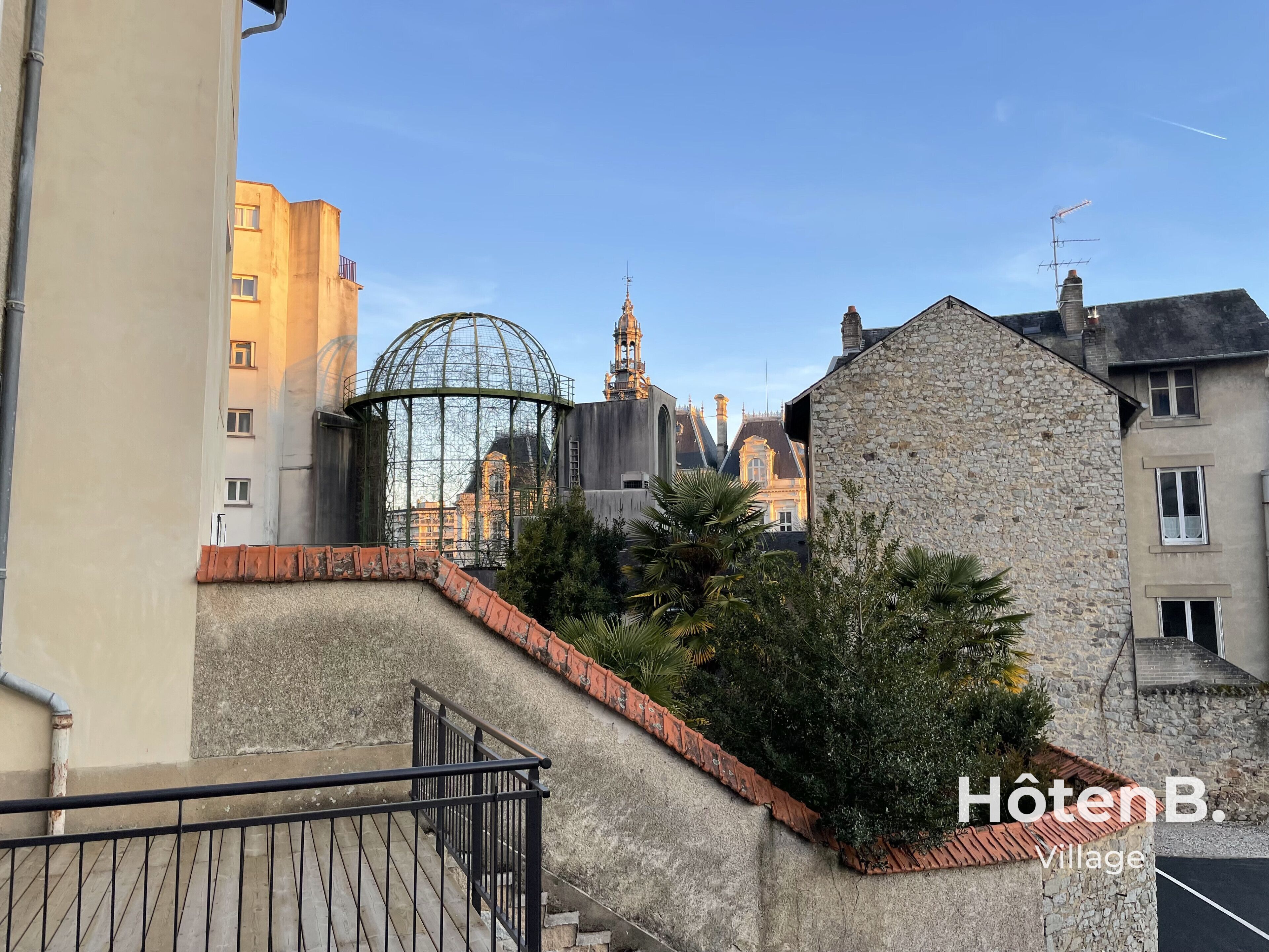 Une vue d’un bâtiment à la façade en pierre, surmonté d’une structure en forme de dôme de verre, et d’un escalier menant à l’étage supérieur.