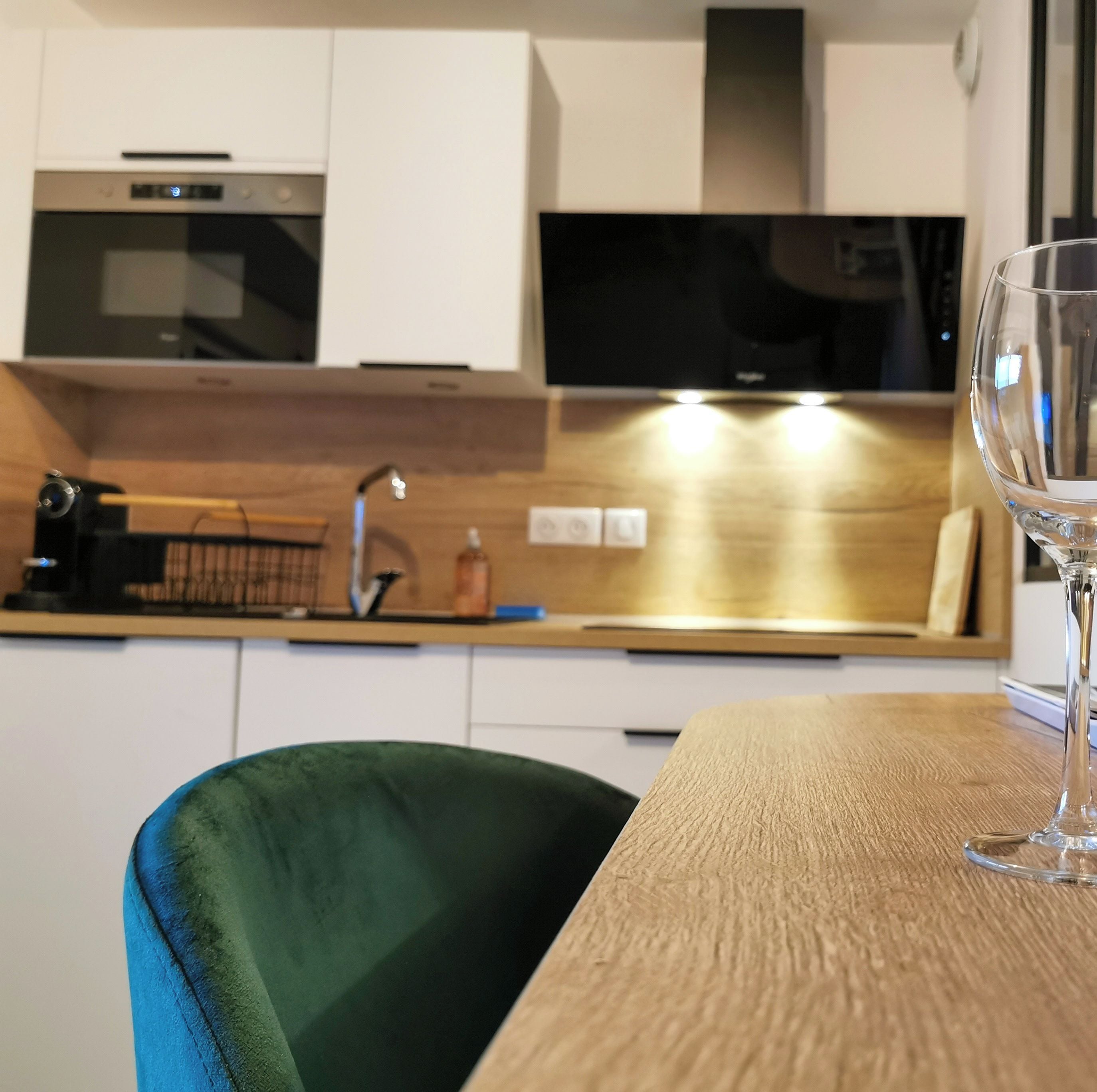 Een moderne keuken met een wijnglas en fles op tafel.