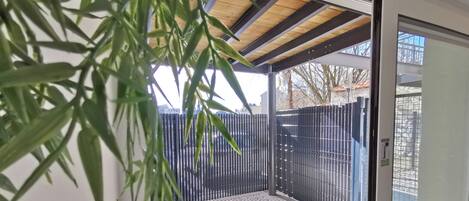 Un espace extérieur moderne et abrité, doté d’un plafond en bois et d’une rambarde en métal, offrant une vue sur les environs.