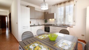 A modern kitchen with white cabinets, a gas stove, and a dining area with a table set for two.