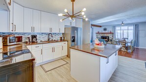 Una cocina moderna con armarios blancos, una isla central y una araña.