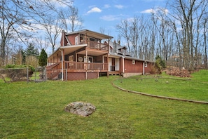 A two-story wooden house with a balcony, a fenced yard, and a small pond. - SAUNA | GAMEROOM | SPACIOUS | POCONO RETREAT | BBQ (East Stroudsburg)