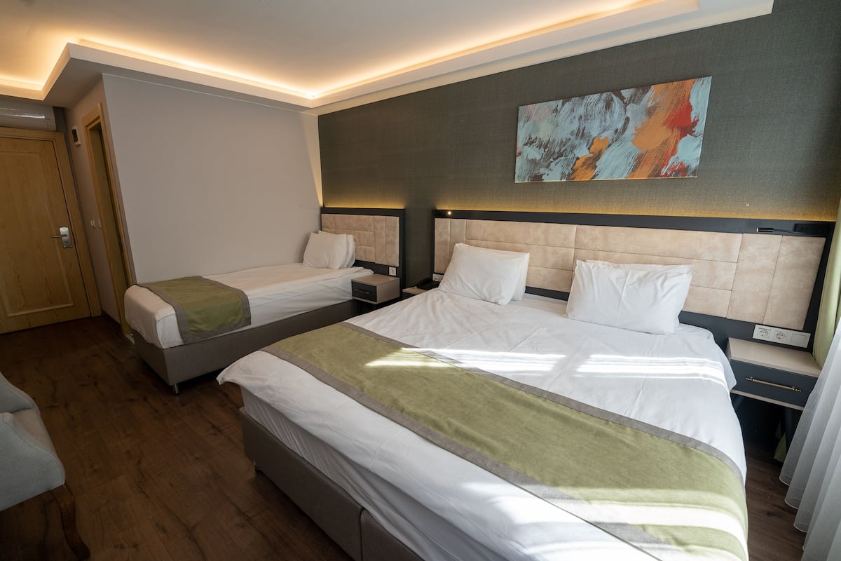 Ein Hotelzimmer mit zwei Betten, einem großen Gemälde an der Wand und einer Holztür.