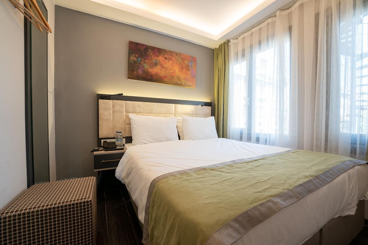Ein Hotelzimmer mit einem großen Bett, einem Nachttisch, einer Bank und einem Bild an der Wand.