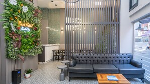 A modern lobby with a black leather sofa, a wooden coffee table, a neon sign, and a vertical garden. - Best Hotel Kadikoy (Istanbul)