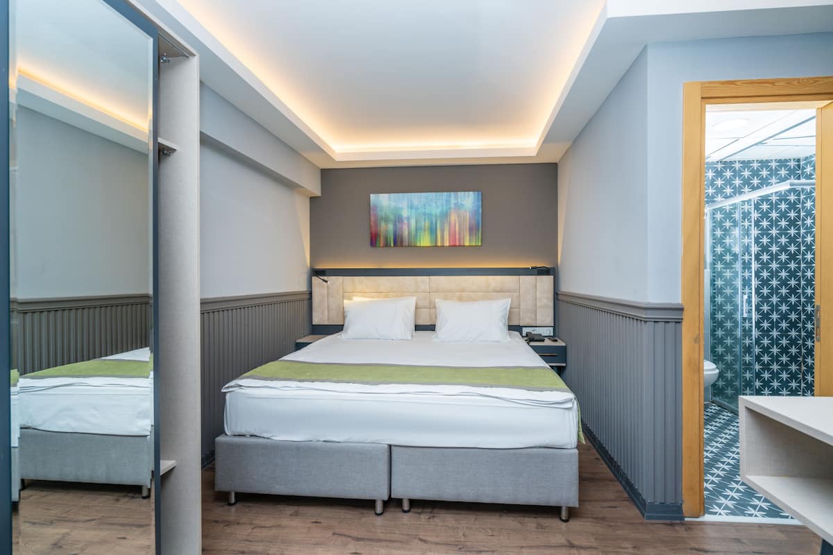 Ein Hotelzimmer mit einem Bett, Nachttischen, einem Spiegel und einem Bild an der Wand.
