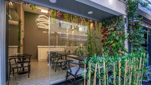 A modern hotel lobby with glass doors, a seating area with tables and chairs, and a vertical garden with various plants and flowers. - Best Hotel Kadikoy (Istanbul)