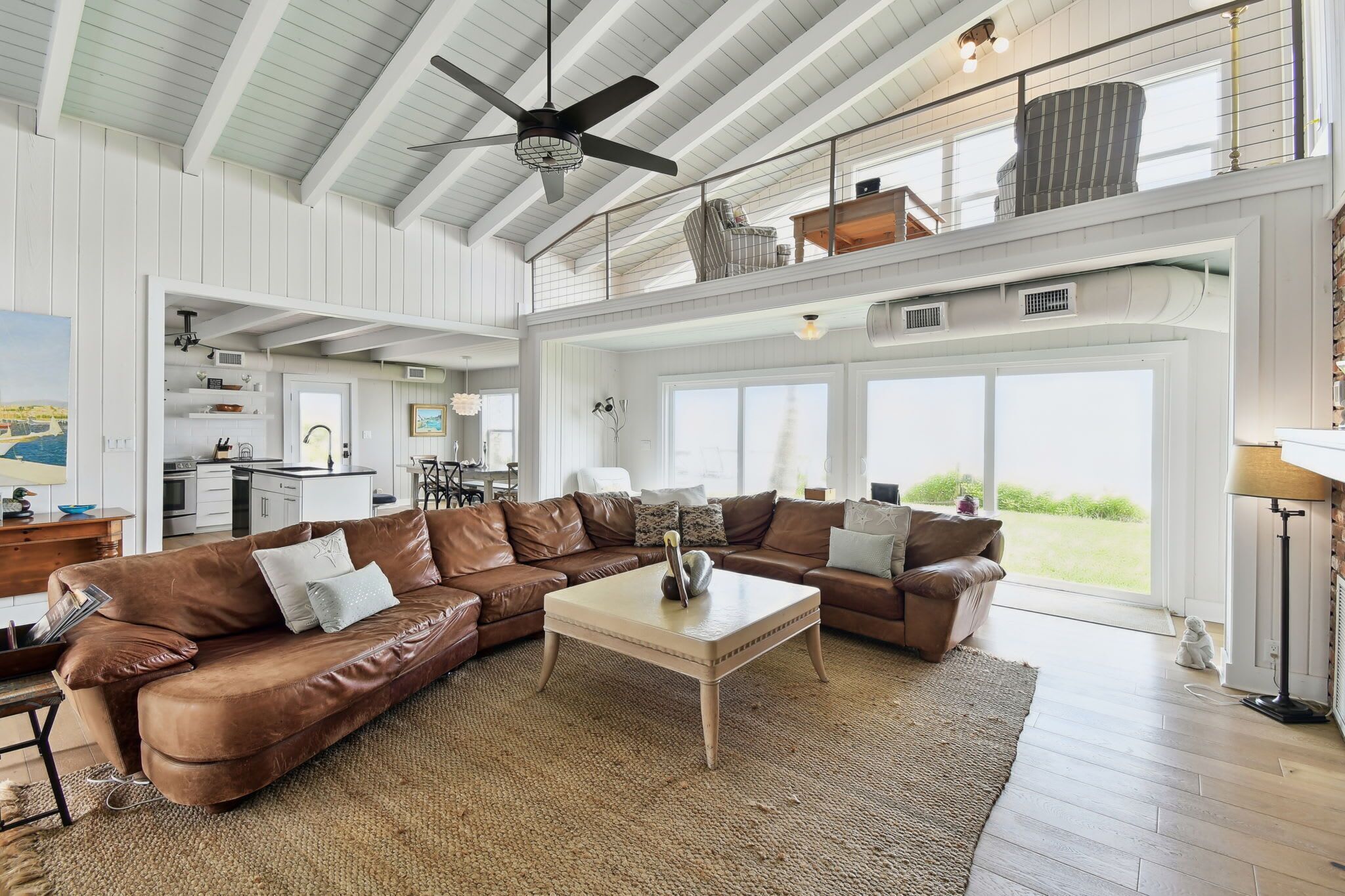 A spacious living room with a large sectional sofa, a coffee table, and a ceiling fan.