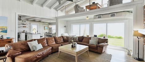 A spacious living room with a large sectional sofa, a coffee table, and a ceiling fan.