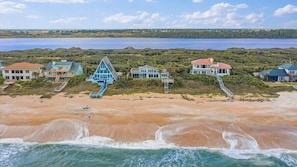 A coastal property with multiple houses, a beach, and a view of the ocean.