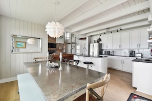 A spacious kitchen with white cabinetry, a large island, and a hanging light fixture.