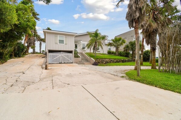 A residential street with houses, a white picket fence, and palm trees.