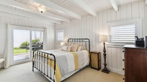 Quarto com cama, mesa de cabeceira, abajur e cômoda.