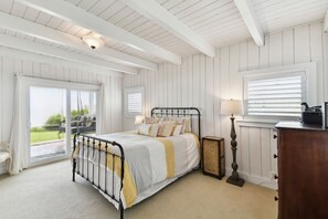 A bedroom with a bed, a nightstand, a lamp, and a dresser.