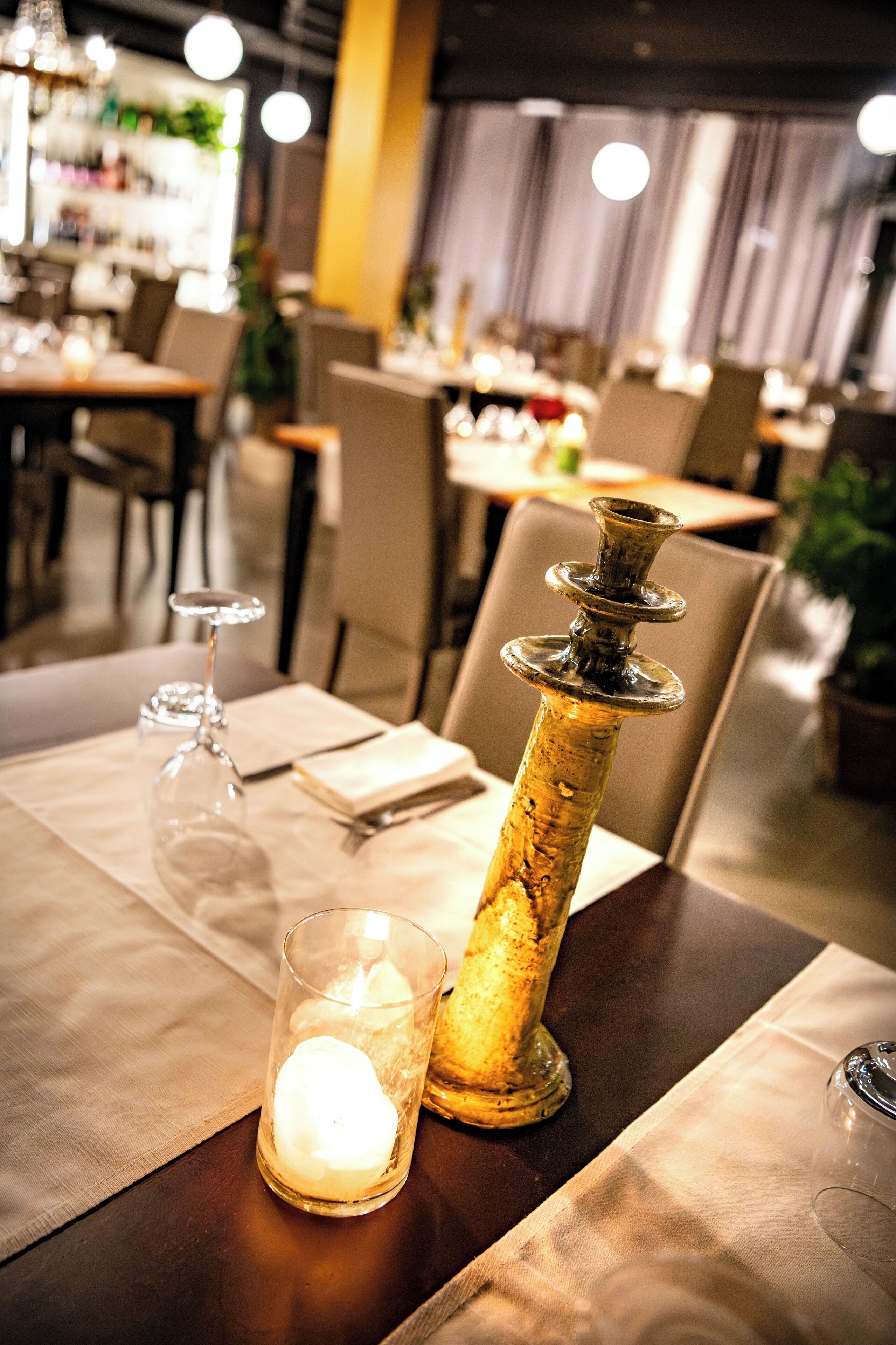 Een eettafel met een kaars, een glas en een decoratieve fles.