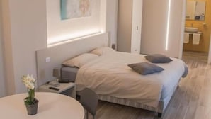 Un dormitorio moderno con cama, mesita de noche y una mesa redonda con sillas.