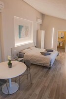 Quarto moderno com cama, mesa de cabeceira e uma mesa redonda com cadeiras.
