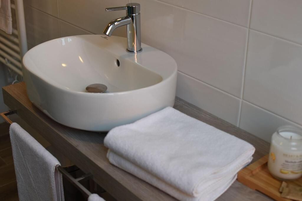 A bathroom with a white sink, a towel rack, and a candle on the countertop.